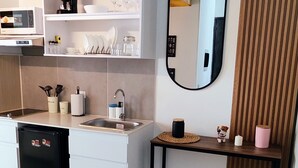 Een moderne keuken met witte kasten, een zwarte koelkast en een houten aanrecht.
