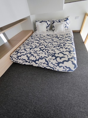 A bed with a patterned bedspread, a wooden headboard, and a dark carpeted floor. - Elegante Loft en Chapinero (Bogotá)