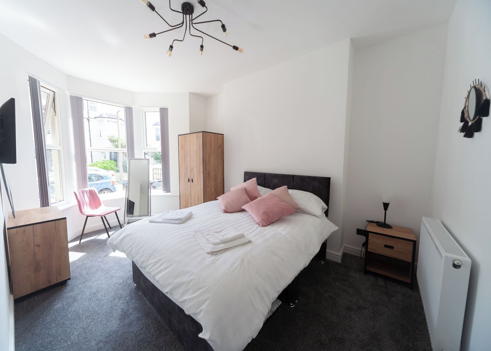 Ein Schlafzimmer mit Bett, Nachttisch, Stuhl, Kleiderschrank und Fenster.