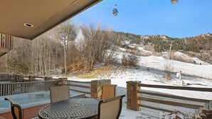 A covered outdoor seating area with a hot tub, chairs, and a view of a snowy landscape and mountains. - Aspen Alps Three bedroom condo  - ski in / out of Aspen Mountain & Hot Tub (Aspen)