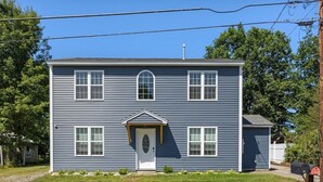 A two-story house with a front porch, a garage, and a mailbox. - Large Private Yard, 4br home, Walk to town center (Meredith)