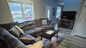 A living room with a sectional sofa, a coffee table, and a flat-screen TV. - Large Private Yard, 4br home, Walk to town center (Meredith)