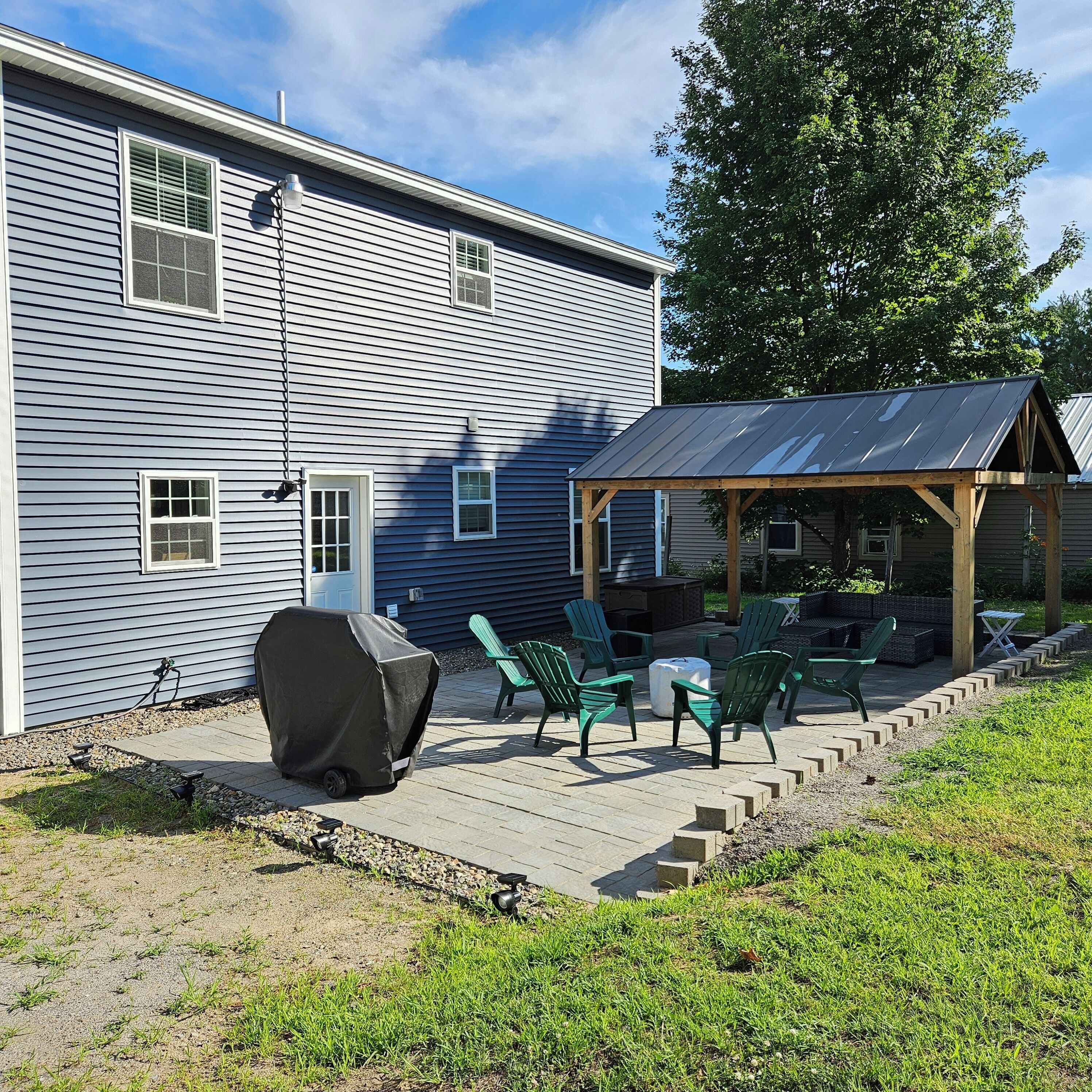 A house with a covered patio area featuring outdoor furniture and a grill.