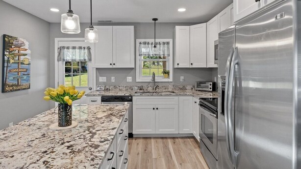 A modern kitchen with white cabinets, a stainless steel refrigerator, and a granite countertop. - Large Private Yard, 4br home, Walk to town center (Meredith)