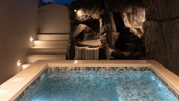 En moderne indendørs swimmingpool med en klippevæg og en trappe, der fører op til et højere niveau.