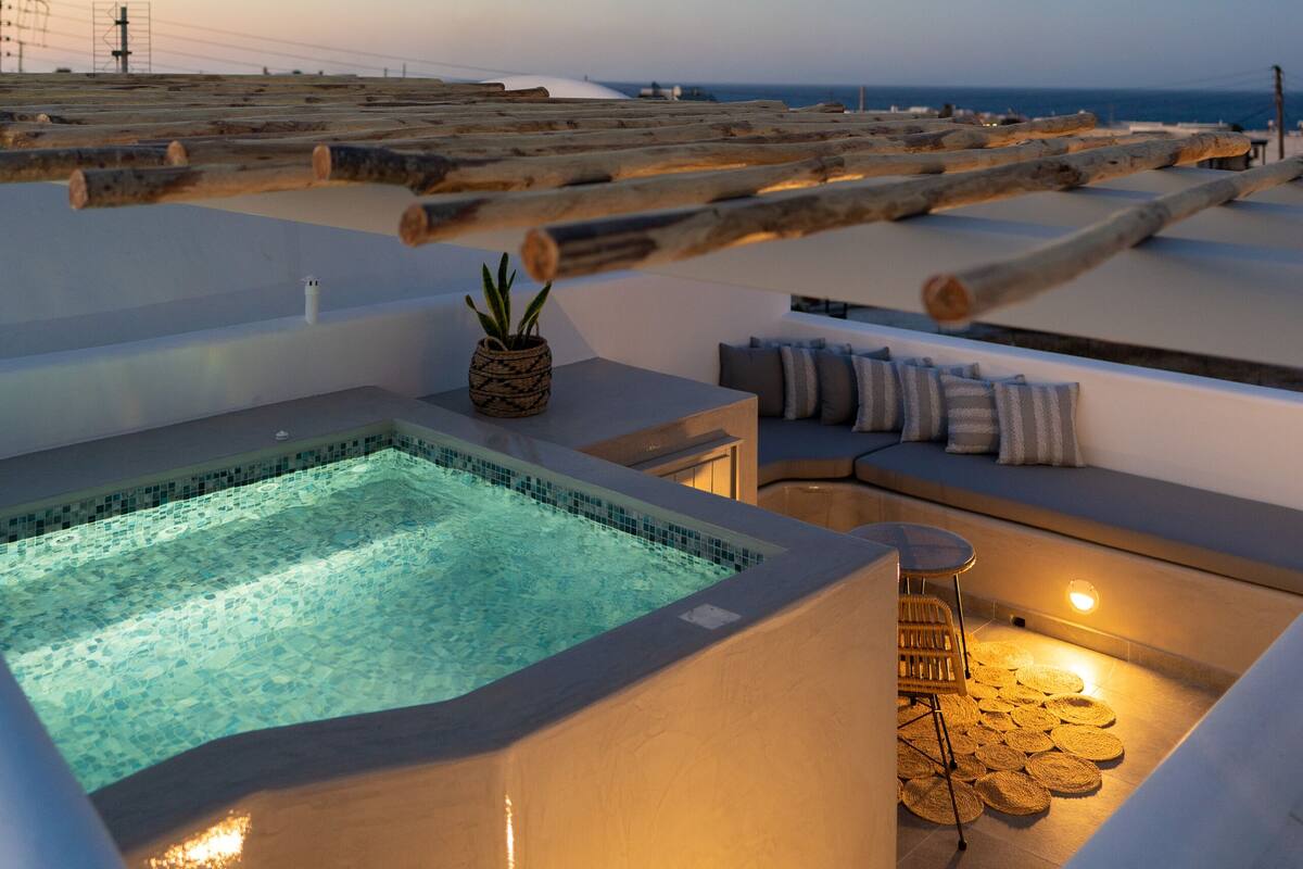 Uma área de piscina no terraço, com espaço para sentar e vista para o mar.