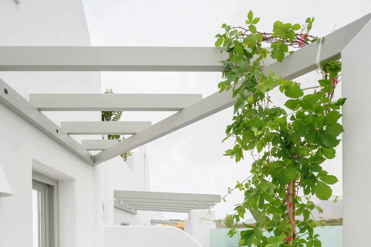 Um espaço exterior moderno com hidromassagem, uma pérgula com plantas trepadoras e vista para a região.