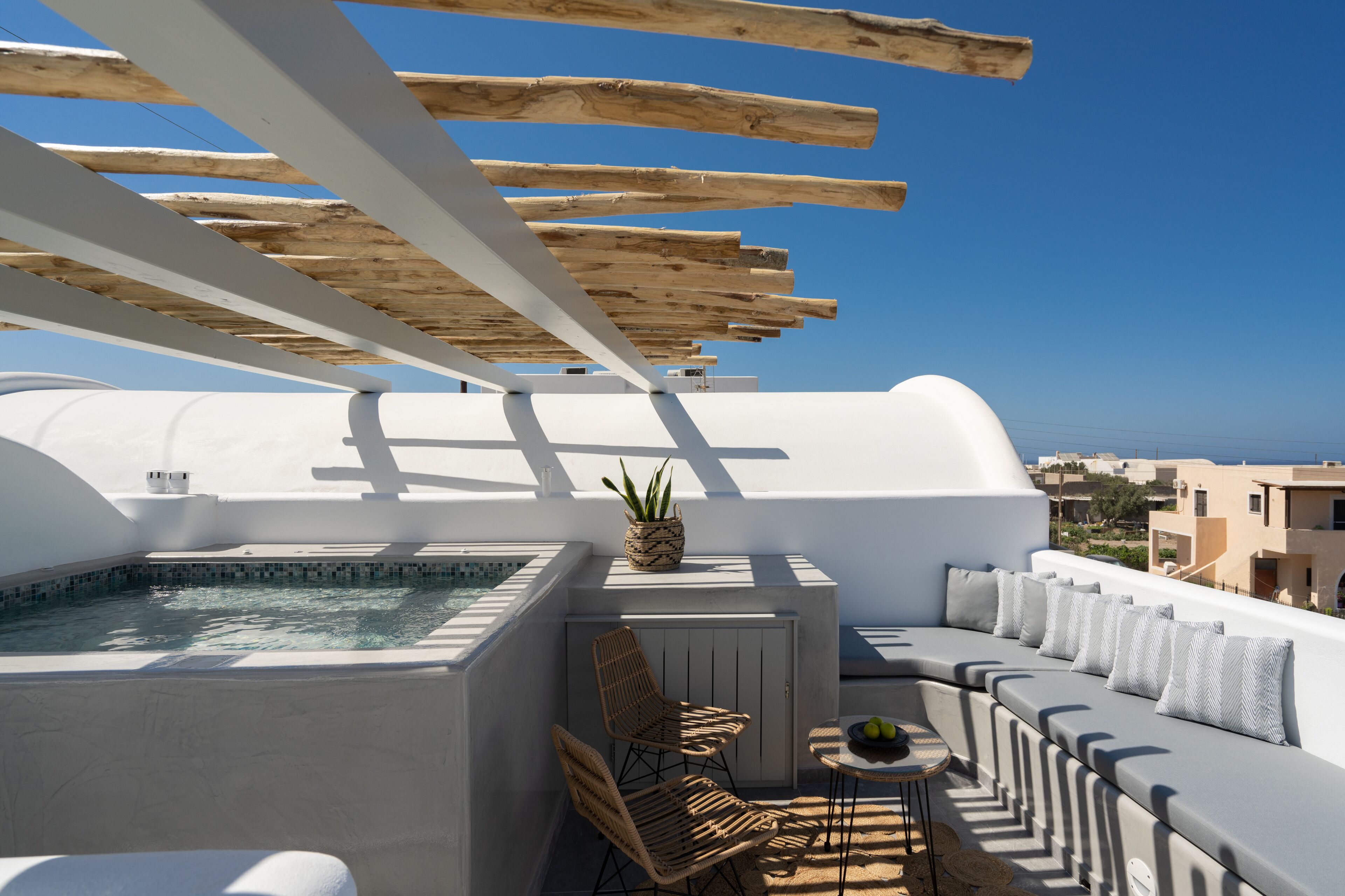 A rooftop terrace with a hot tub, seating area, and a view of the sea.