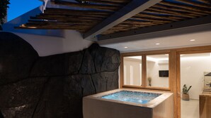 Et moderne spaområde med jacuzzi, klippevæg og træloft.
