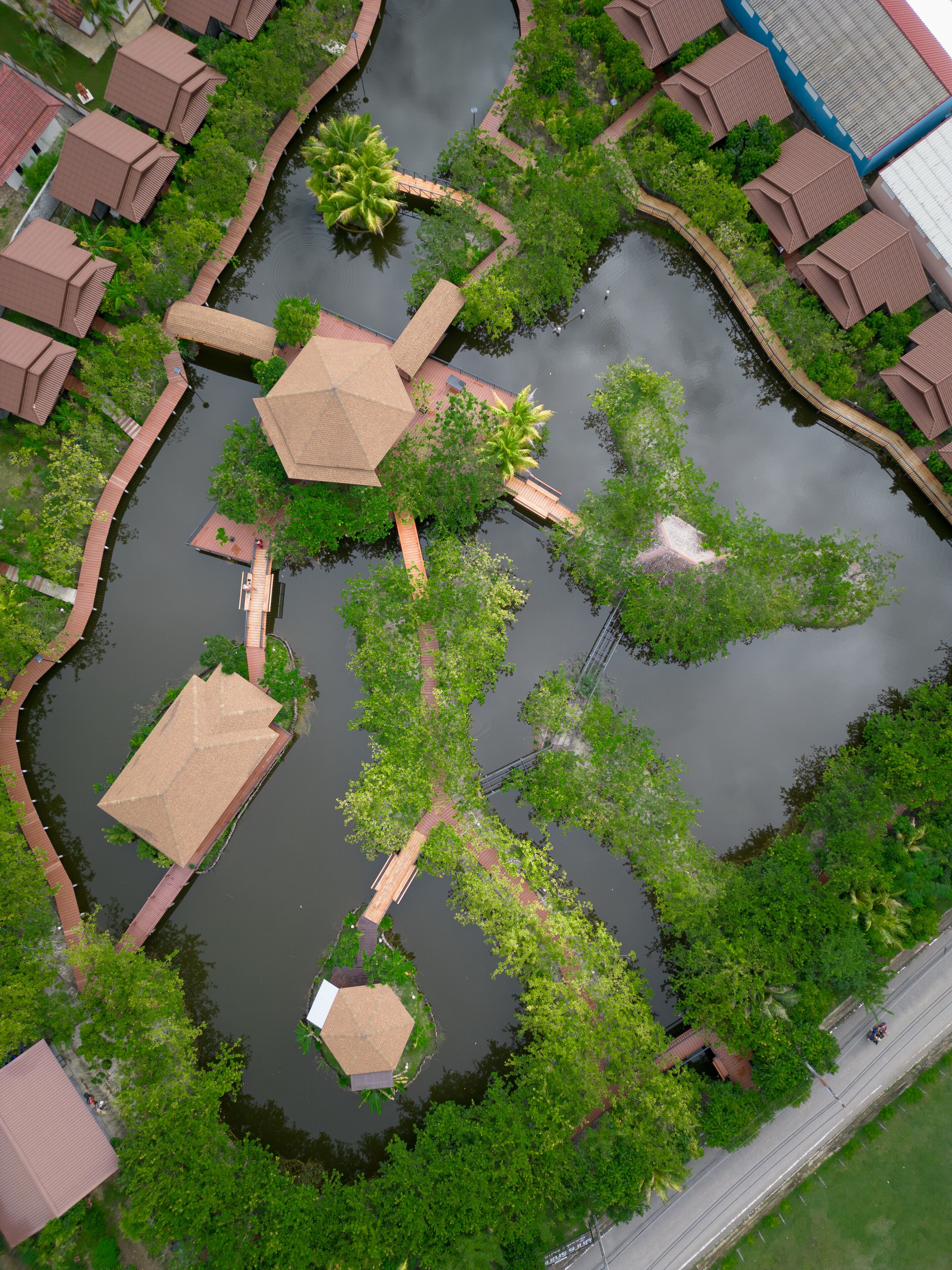 An aerial view of a water park with interconnected walkways, palm trees, and buildings with red roofs.