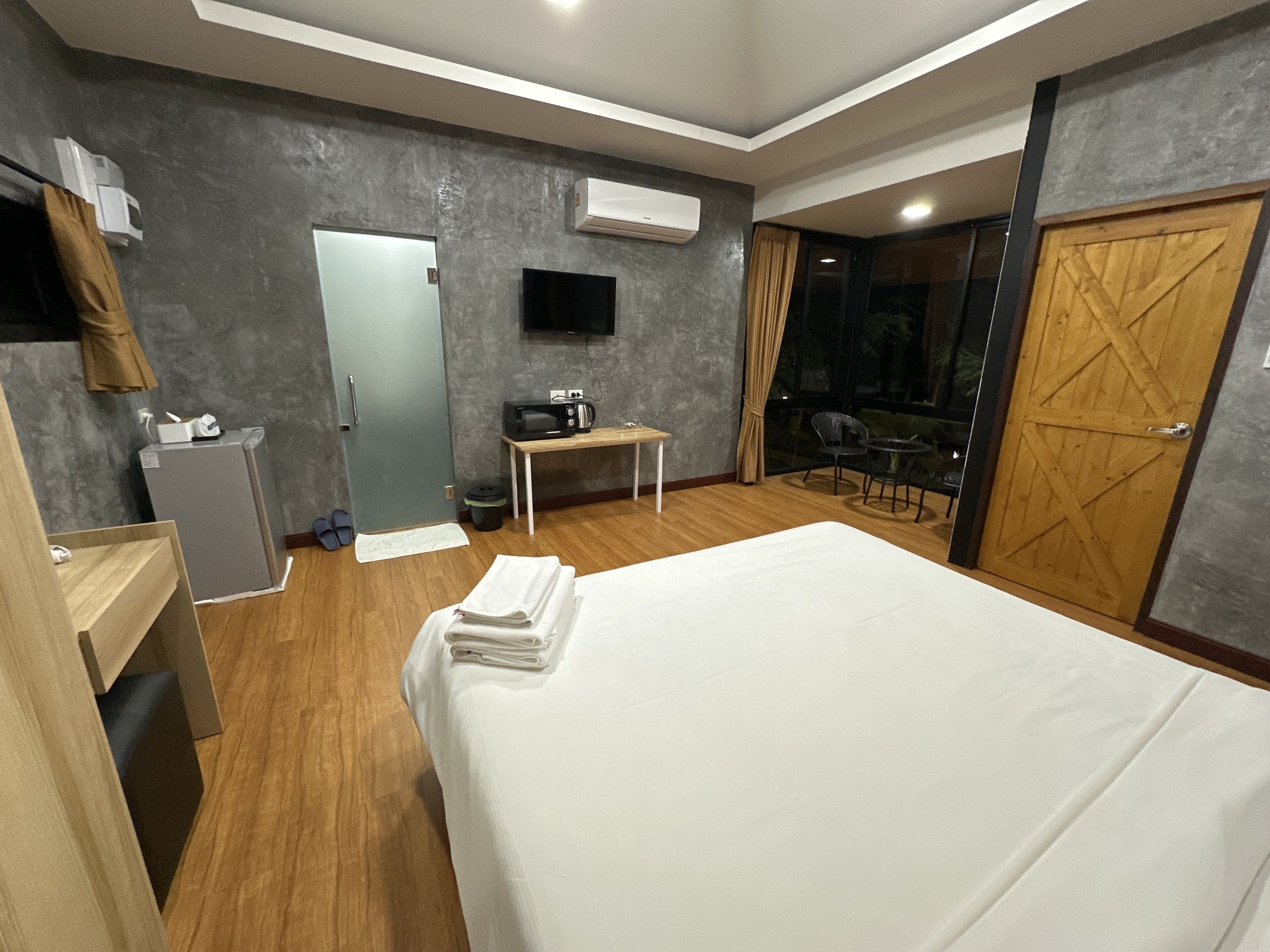 A hotel room with a bed, a desk, a TV, a wardrobe, and a window with curtains.