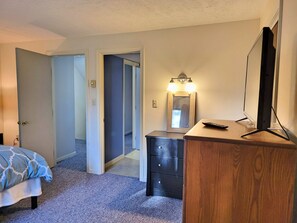 A bedroom with a bed, dresser, mirror, and a TV on a stand. - Close to shops/dining/town access. Pet-friendly, Wifi, deck. A0040 by LRS (Woodstock)