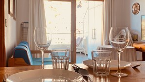 A dining area with a table set for two, including wine glasses, water glasses, plates, and cutlery.