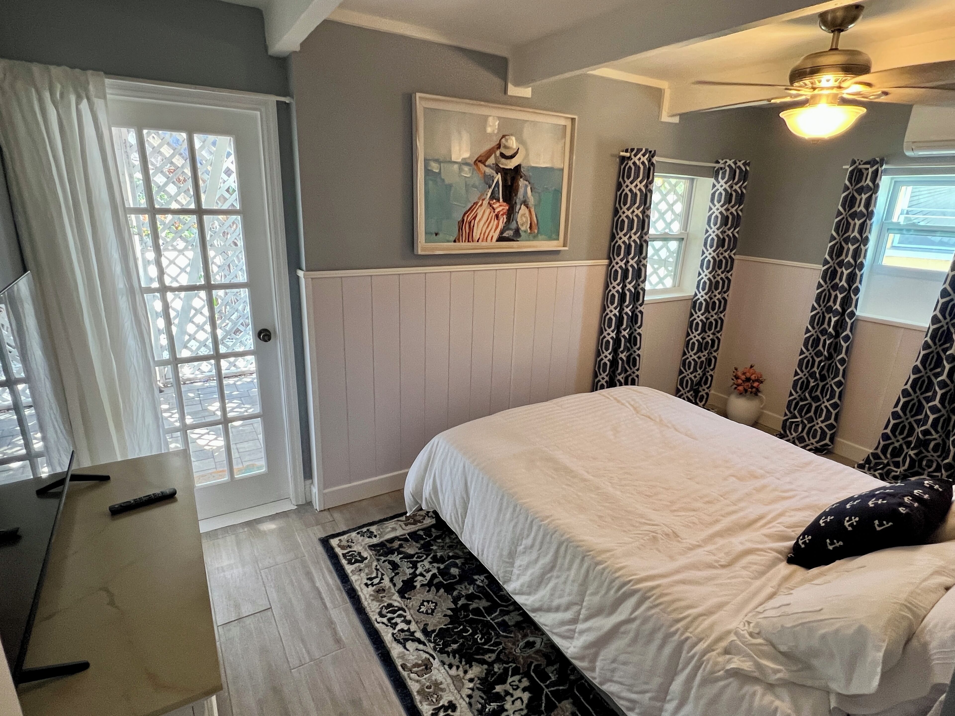 A bedroom with a bed, a desk, and a painting on the wall.