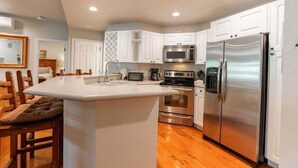 Una cocina moderna con armarios blancos, electrodomésticos de acero inoxidable y una isla central.