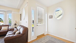 A living room with a brown leather sofa, a patterned rug, and a white door with blinds. - Talal R Muhtaseb (Oceanside)