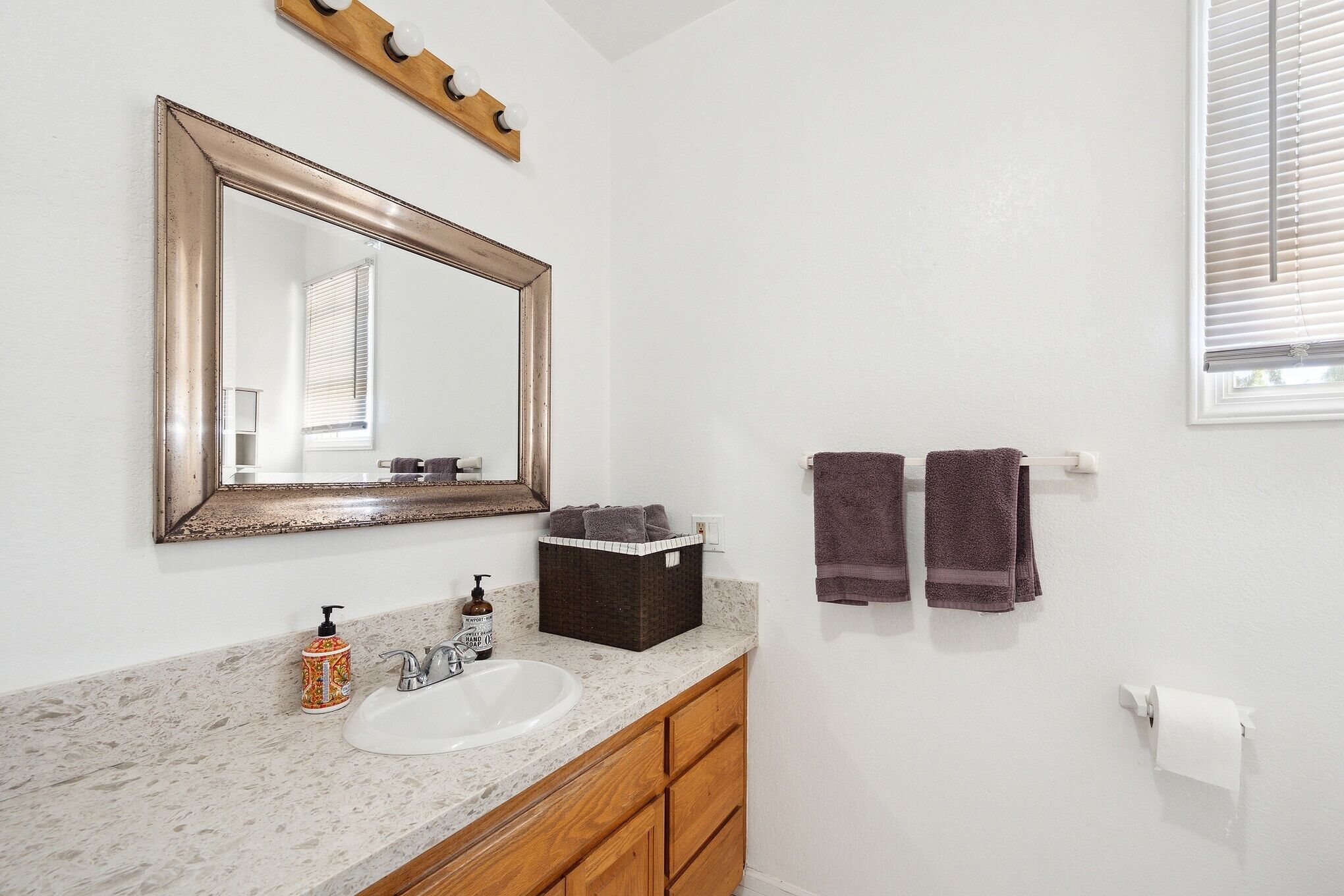 A bathroom with a white sink, wooden cabinets, a mirror, and two towels on a rack.