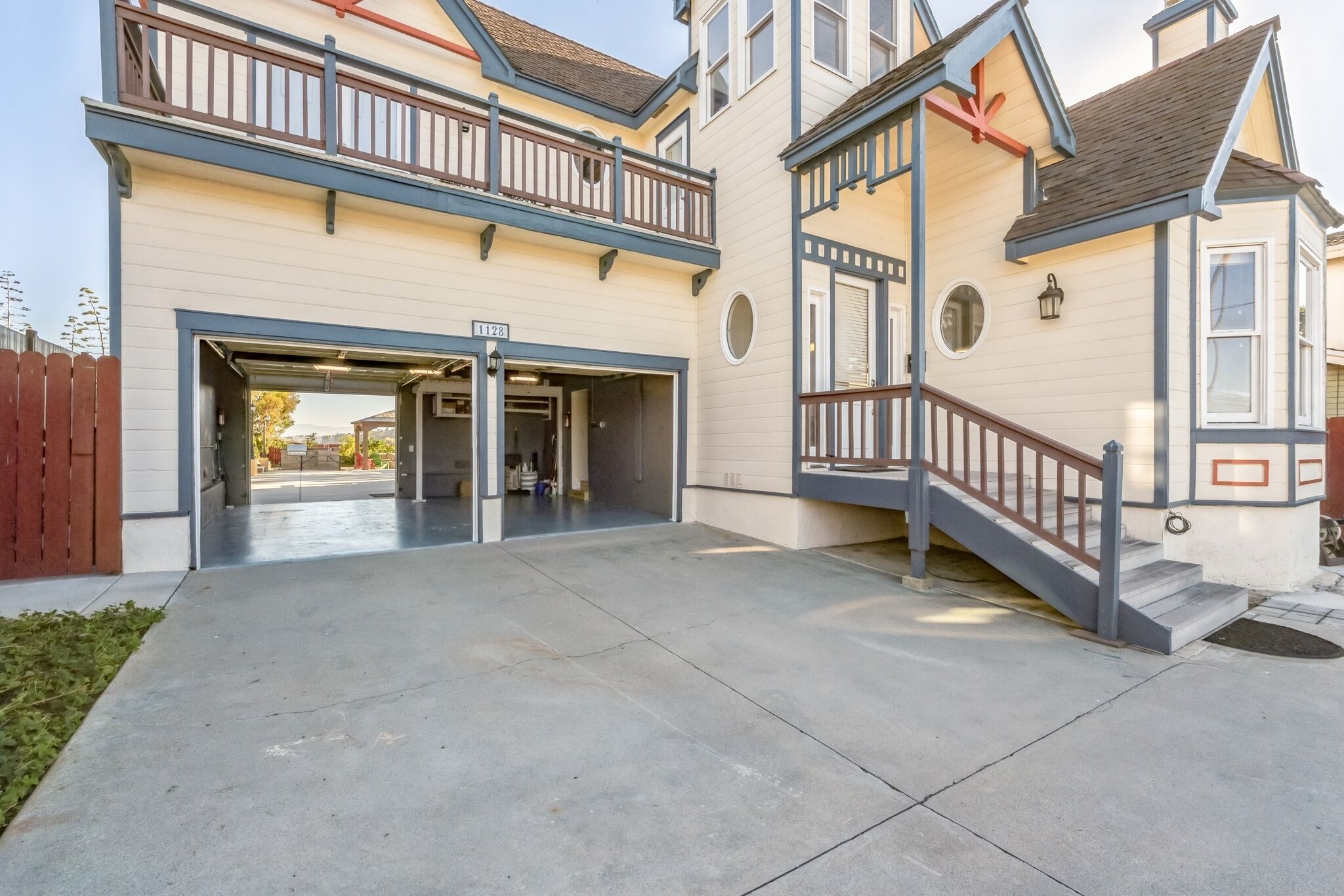 A two-story building with a garage entrance, a balcony, and a staircase leading to the upper floor.