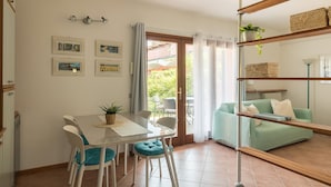 Un comedor con una mesa y sillas, un sofá verde y una estantería con cestas.