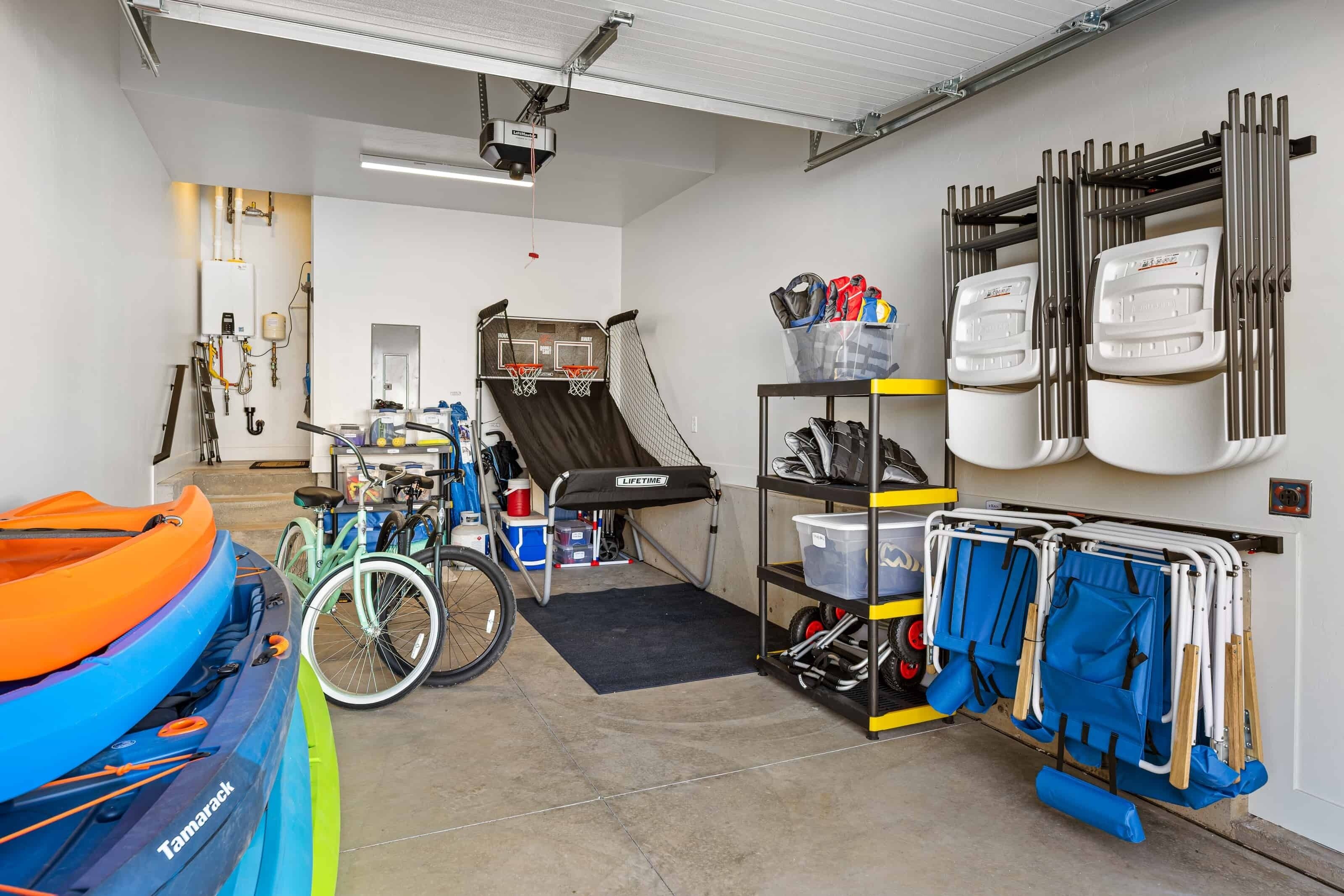 A garage with kayaks, a bicycle, a treadmill, and a storage rack with equipment.