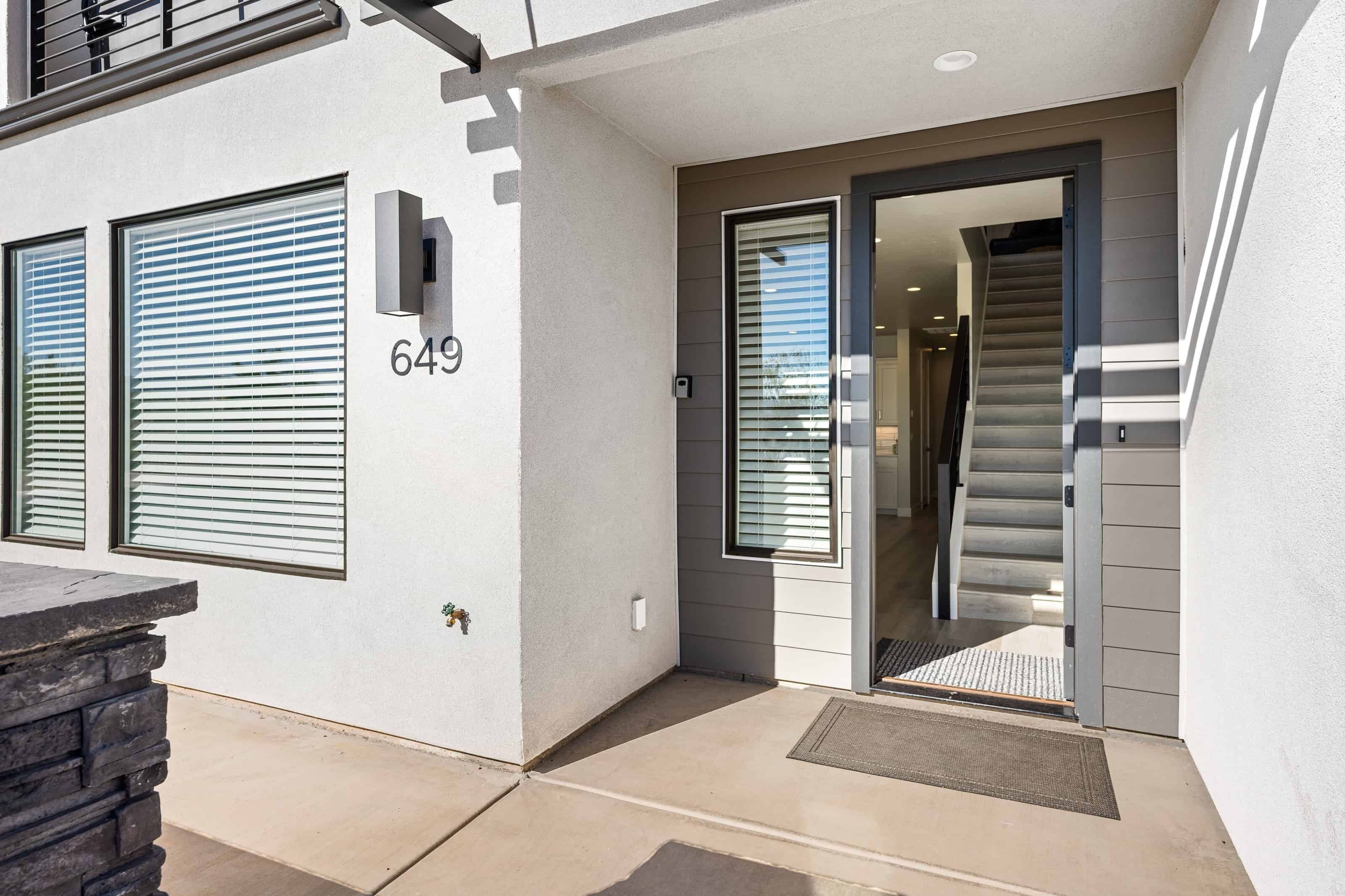 A modern building entrance with a number 649 sign, a staircase, and a door with a glass panel.