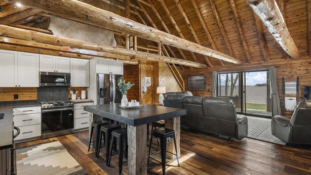 A spacious kitchen with modern appliances, a dining area with a central island, and a cozy seating area with a large window offering a view.