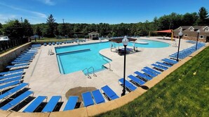 Ein großer Pool im Freien mit blauen Liegestühlen und einem Kiosk.