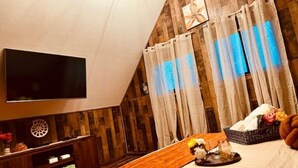 Ein Schlafzimmer mit Fernseher, Holzwänden, einem Bett und Vorhängen.