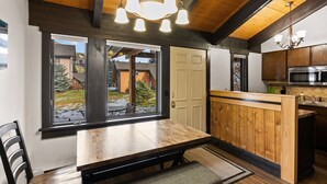 Une cuisine moderne avec une table et un banc en bois, de grandes fenêtres et une vue sur l’extérieur.