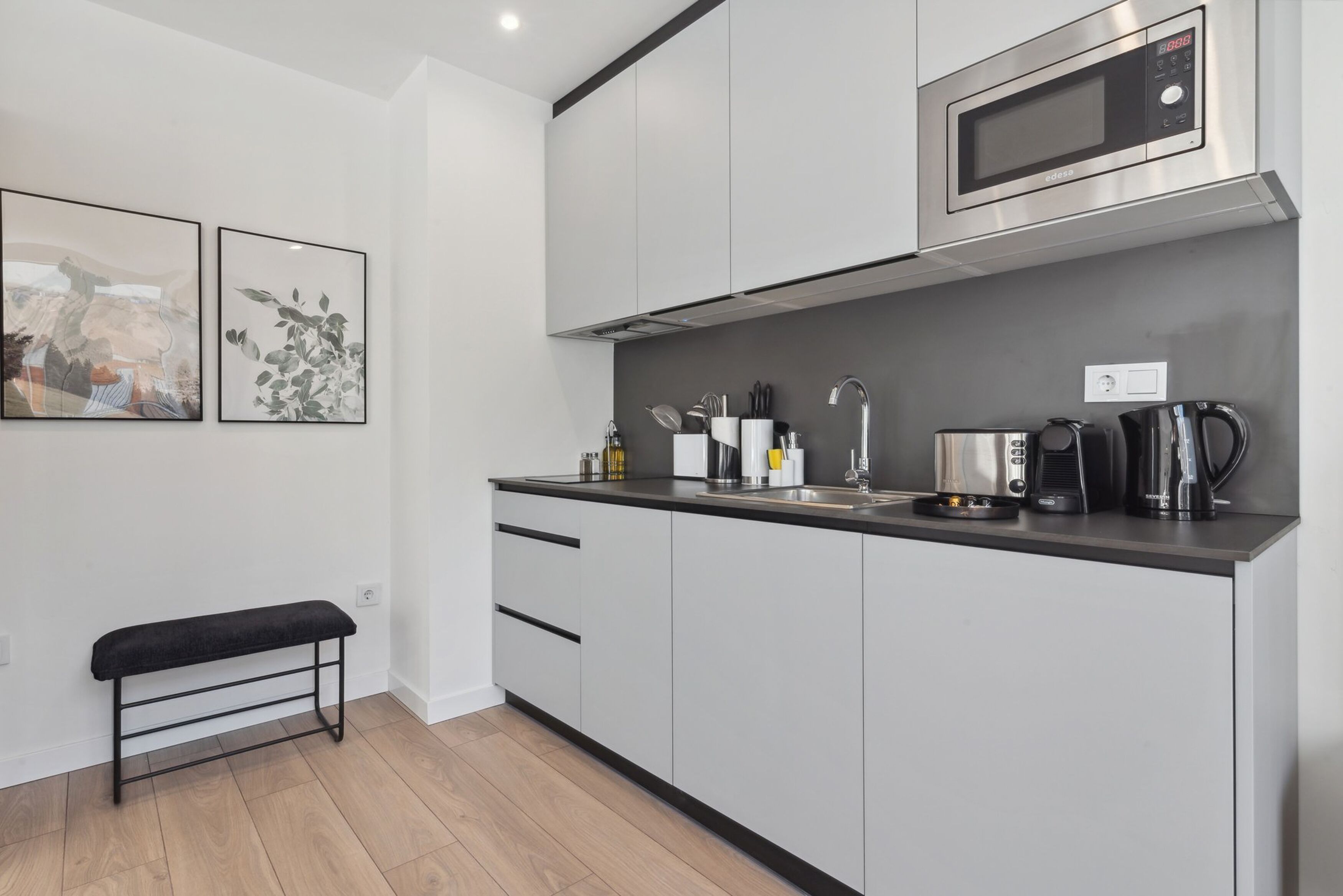 A modern kitchen with a microwave, coffee maker, and utensils on the counter.