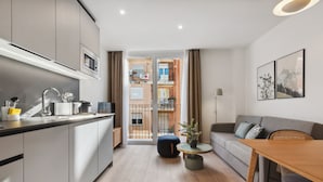 Un apartamento moderno con cocina, comedor y sala de estar. Cuenta con un ventanal grande, un balcón y vistas de la ciudad.