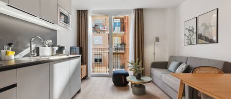 A modern apartment with a kitchen, dining area, and living room. It features a large window, a balcony, and a view of the city.