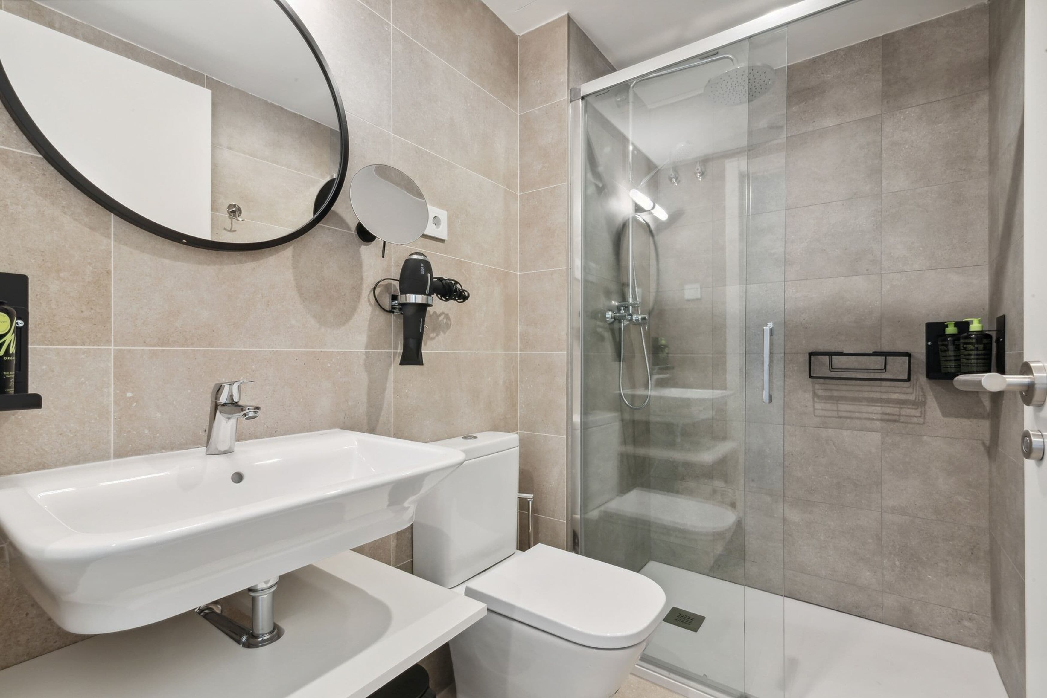 A modern bathroom with a white sink, toilet, and glass shower enclosure.