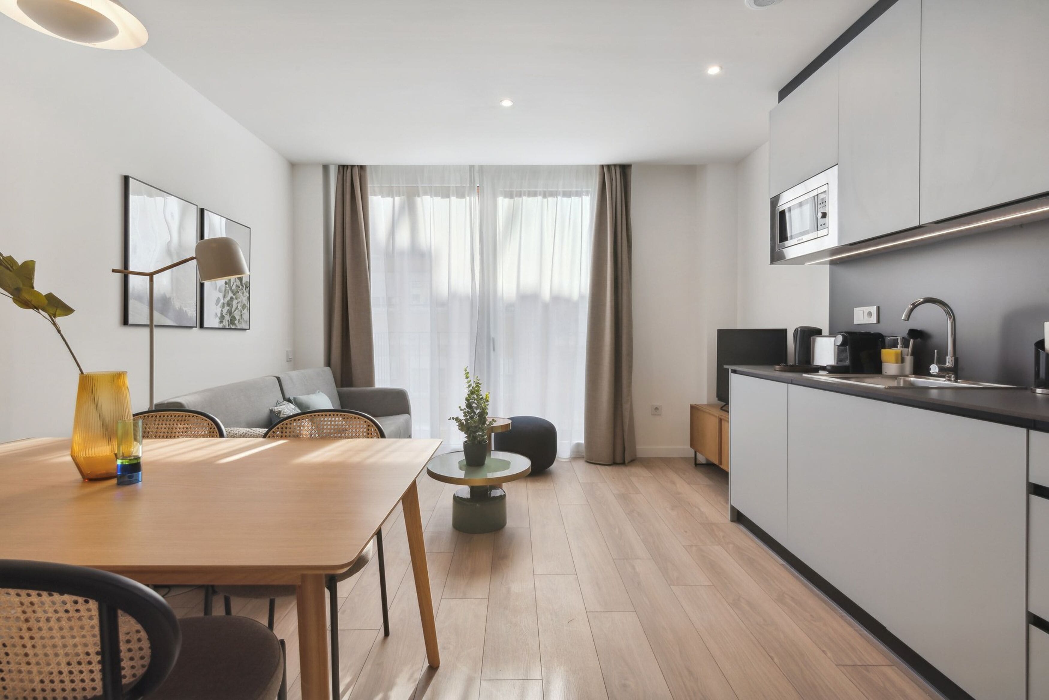 A modern apartment with a dining area, kitchen, and living space.