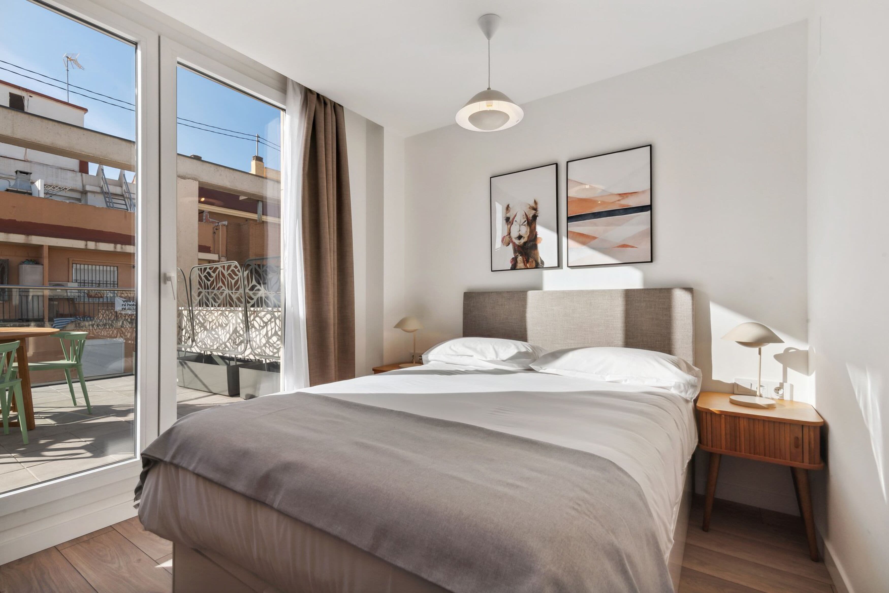 Une chambre moderne avec un grand lit, un balcon offrant une belle vue et deux tableaux encadrés accrochés au mur.