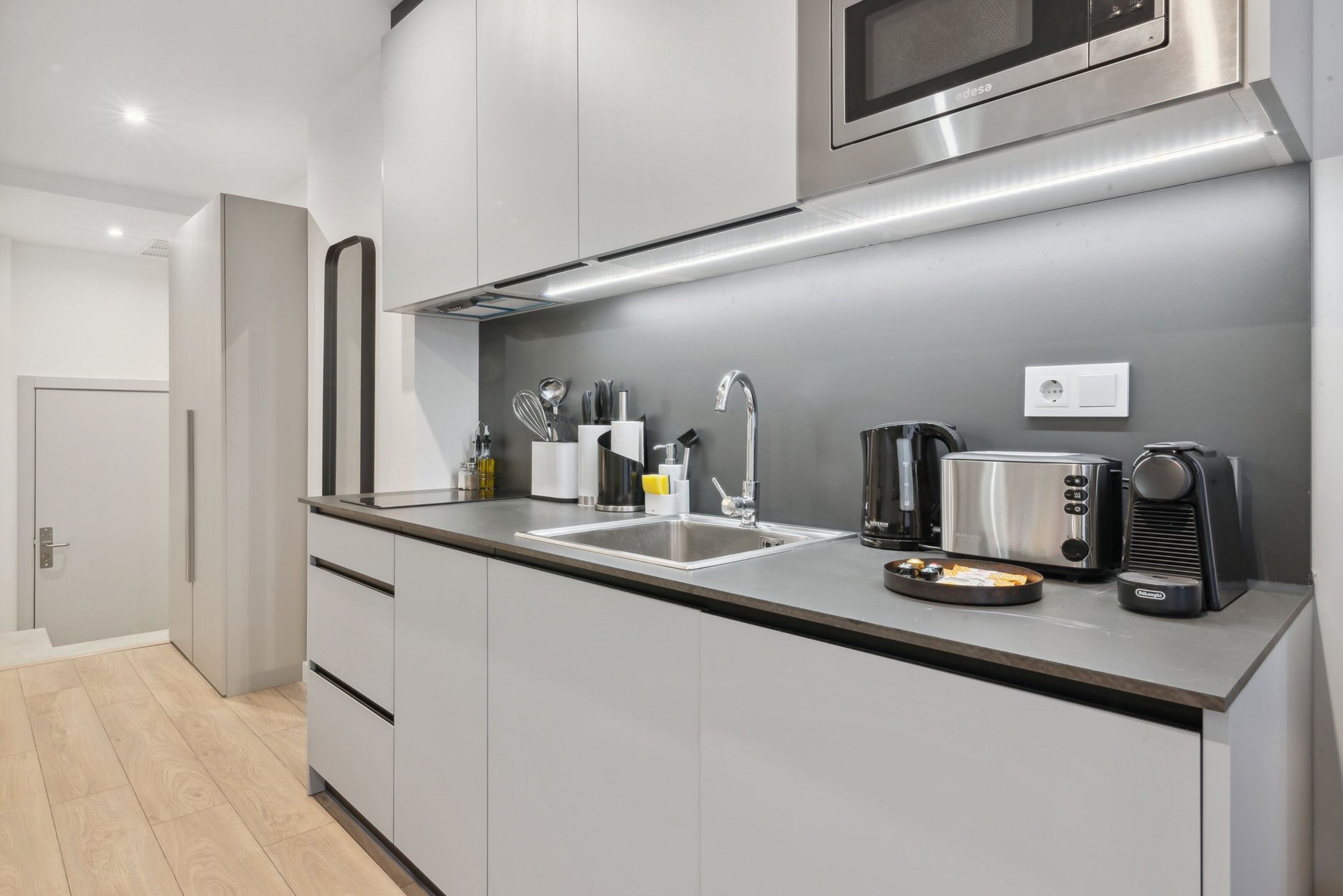 Une cuisine moderne équipée d’appareils électroménagers en acier inoxydable, d’un évier à deux bacs et d’une machine à café.