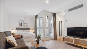Una sala de estar moderna con sofá, televisor, mesa de centro y cama.