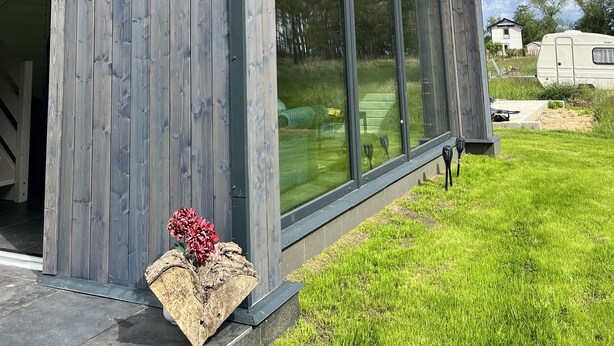 Une maison moderne dotée de grandes fenêtres et d’un toit en pente.