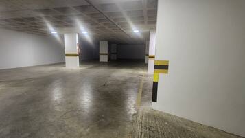 A parking garage with concrete floors and white walls, featuring yellow and black striped columns.