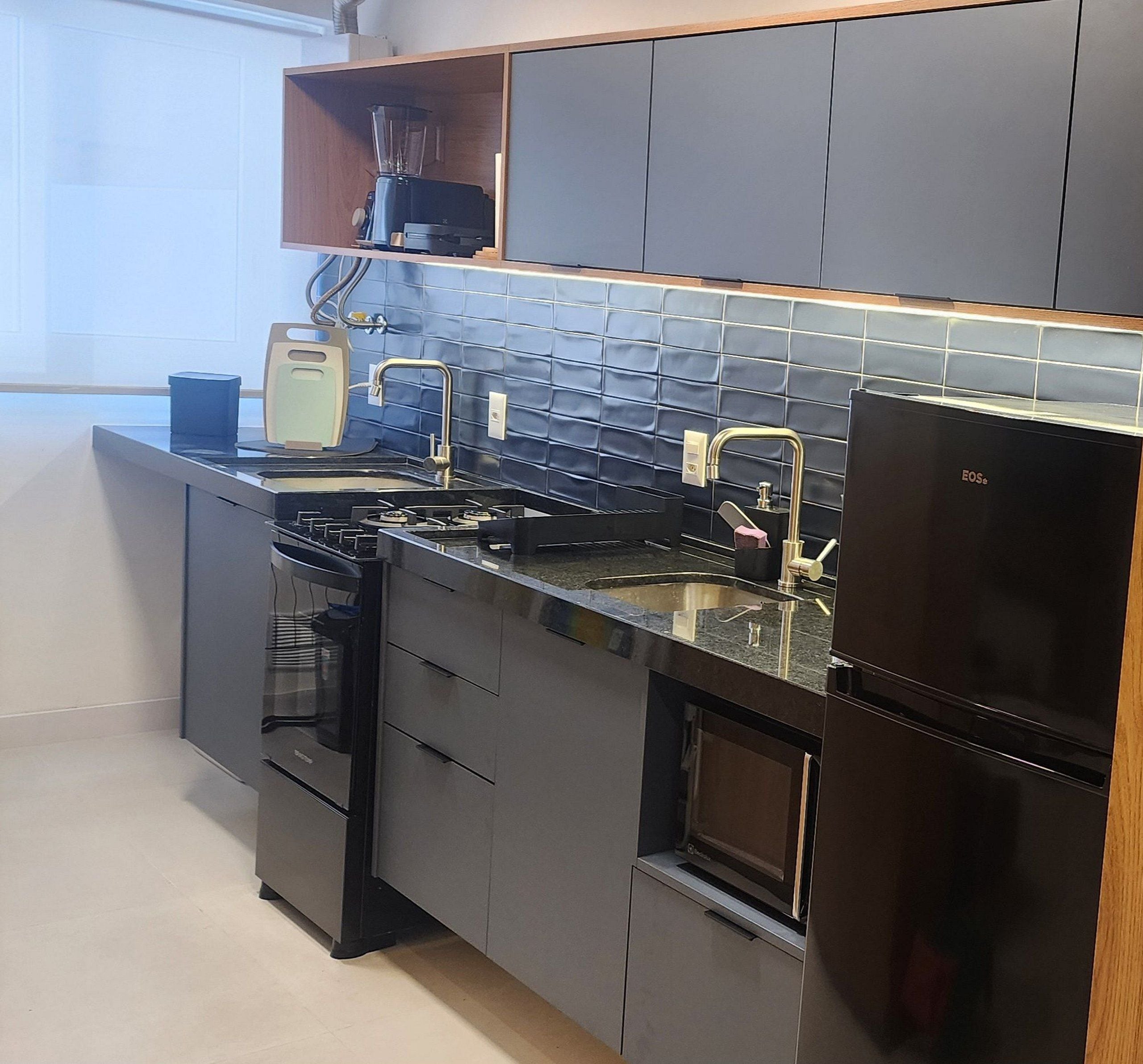 A modern kitchen with a built-in stove, oven, and refrigerator, featuring a blue tiled backsplash and wooden cabinets.