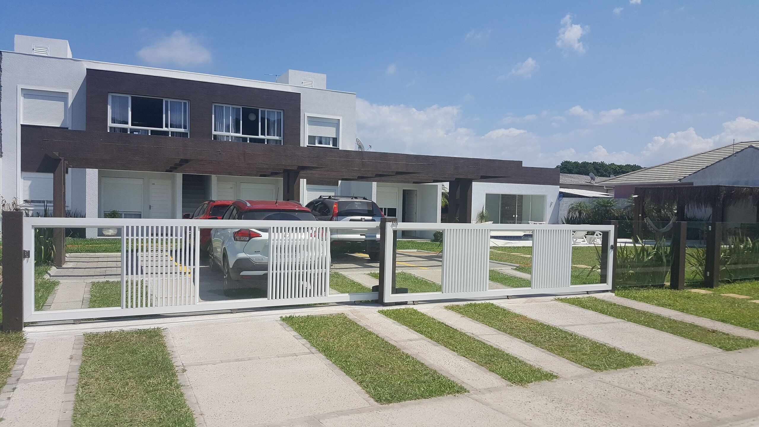 A modern two-story house with a covered driveway and a gated entrance.