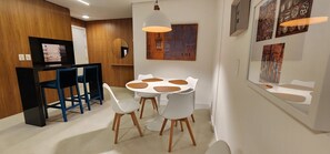 A modern kitchen with a dining area, wooden cabinets, and a round table with chairs. - Atlantida Park Residence (Xangri-La)