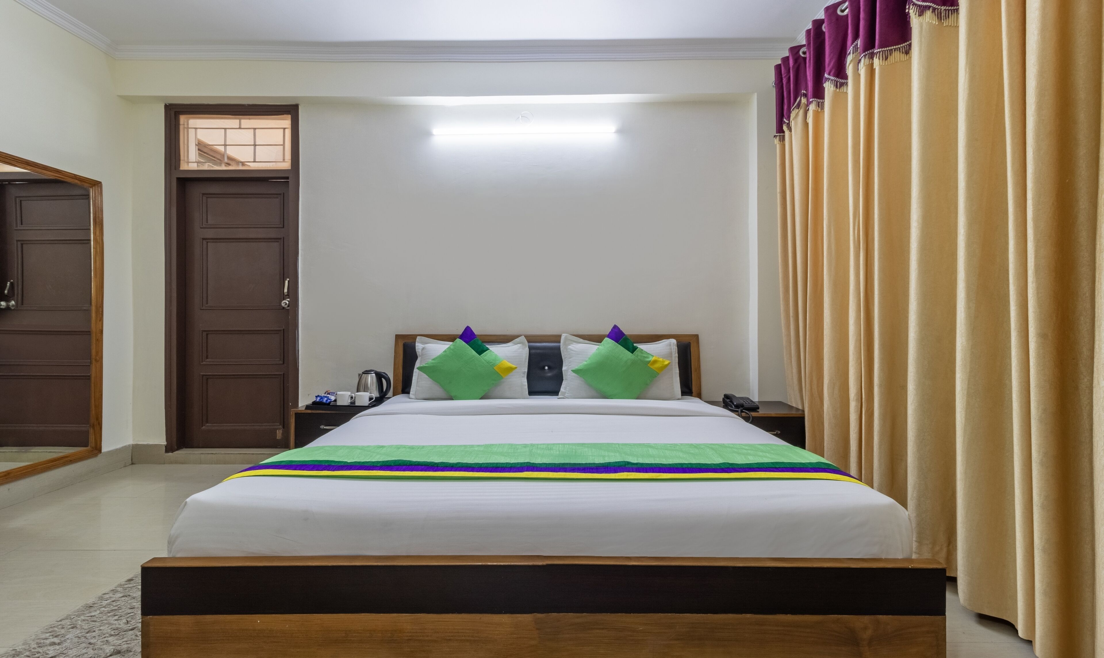Una habitación de hotel ordenada con una cama, una mesita de noche, un teléfono y una puerta.