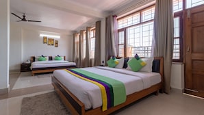 A hotel room with two beds, a ceiling fan, and large windows with curtains. - Treebo Stotrak S N Residency, Mussoorie (Dehradun)