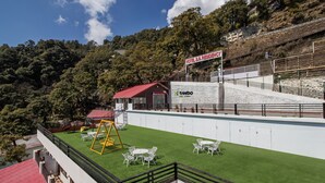 A hotel with a red-roofed building, a swing set, and outdoor seating. - Treebo Stotrak S N Residency, Mussoorie (Dehradun)