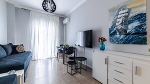 A modern living room with a sofa, TV, and artwork. - Bijou apartment in Glyfada center (Glyfada)