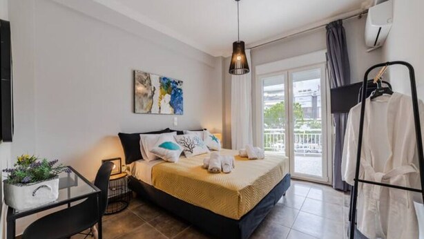 A modern bedroom with a bed, bedside table, and a view of the outdoors. - Bijou apartment in Glyfada center (Glyfada)