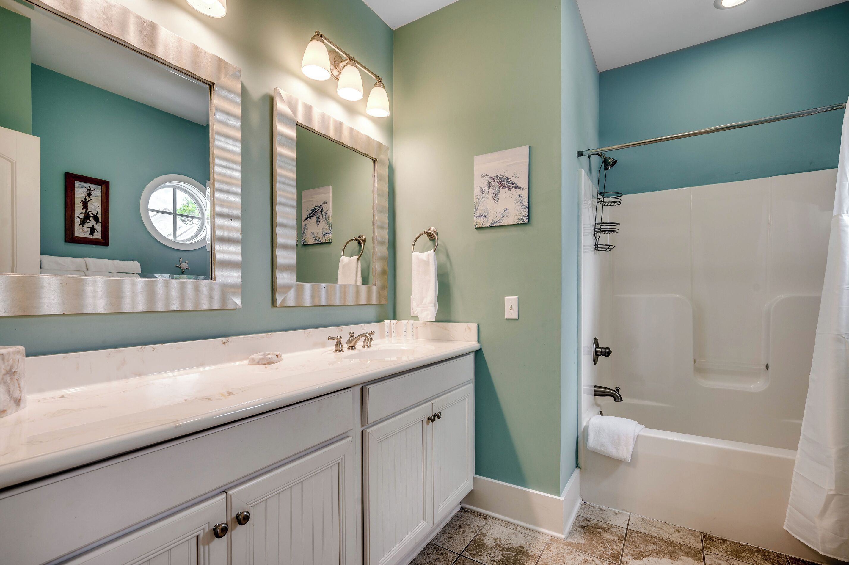 A bathroom with a white vanity, a large mirror, and a bathtub.