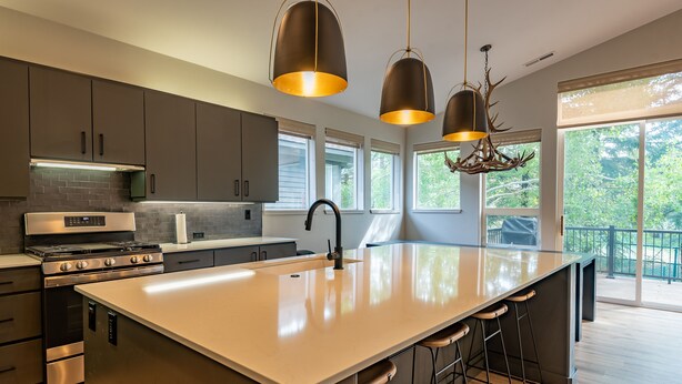 A modern kitchen with a large island, stainless steel appliances, and pendant lighting.