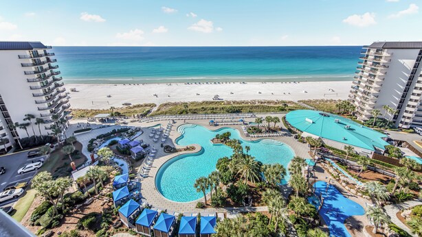 Un resort con una piscina grande, acceso a la playa y edificios altos.